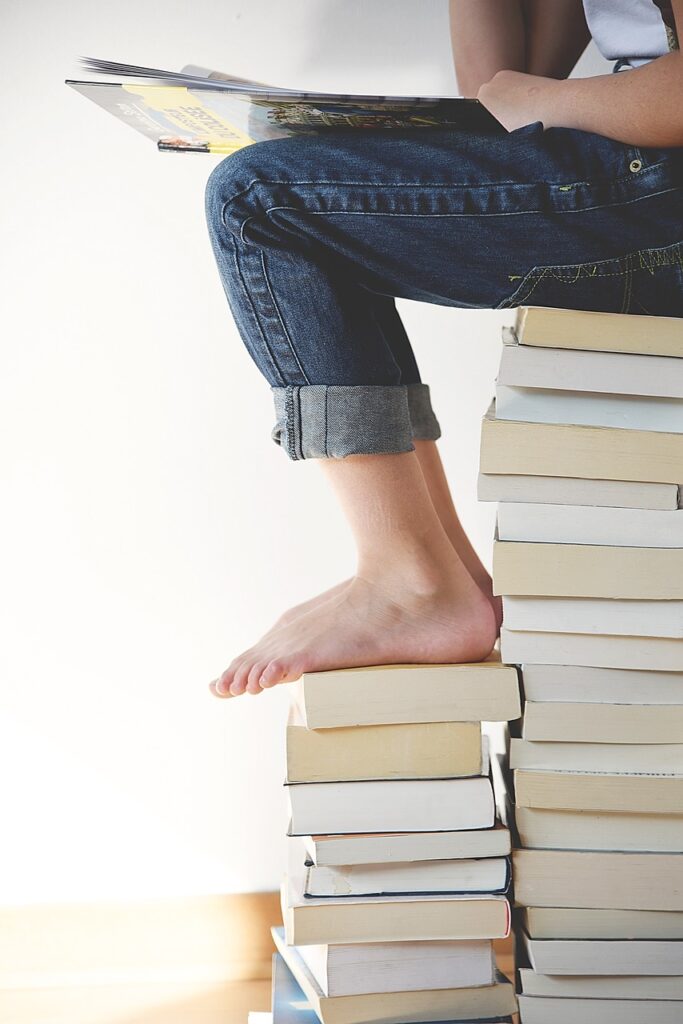 Picture of a person studying whilst seated on a pile of books