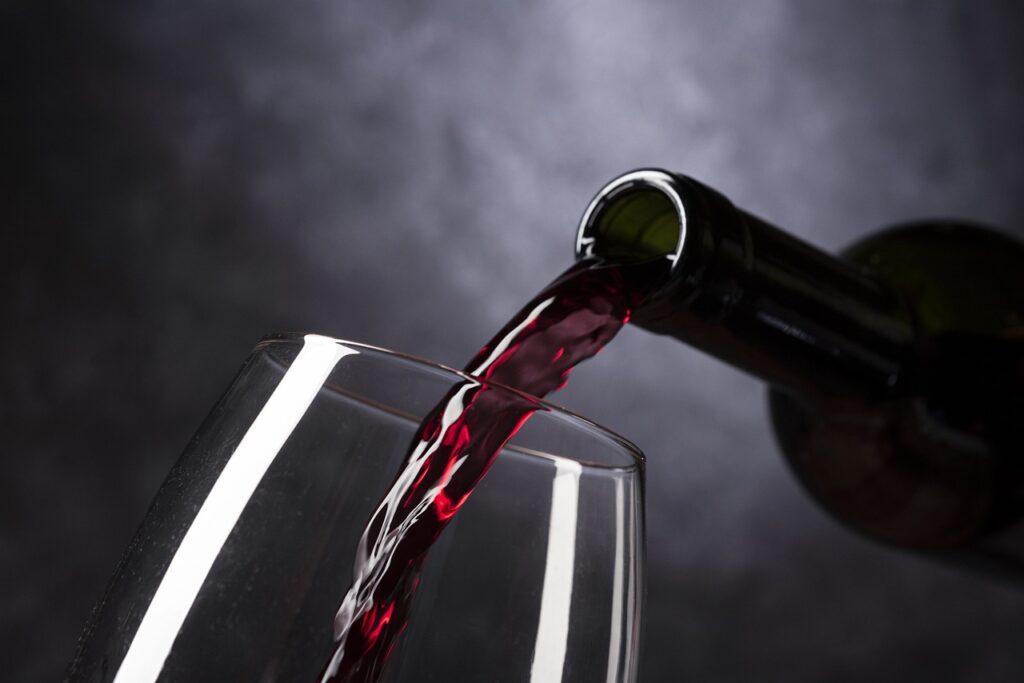 A bottle of red wine emptying into a glass.